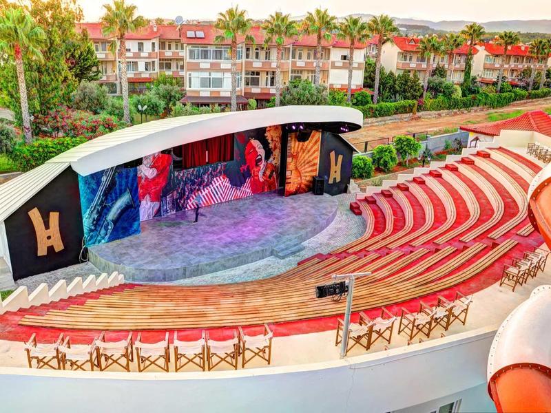 Théâtre en plein air avec scène colorée et gradins rouges dans un complexe hôtelier.