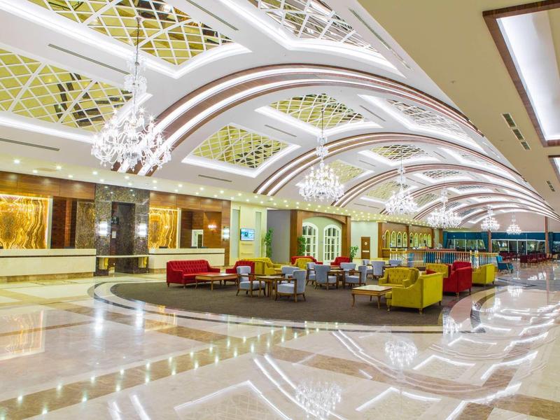 Lobby d'hôtel spacieux avec mobilier coloré sous un plafond voûté moderne éclairé.