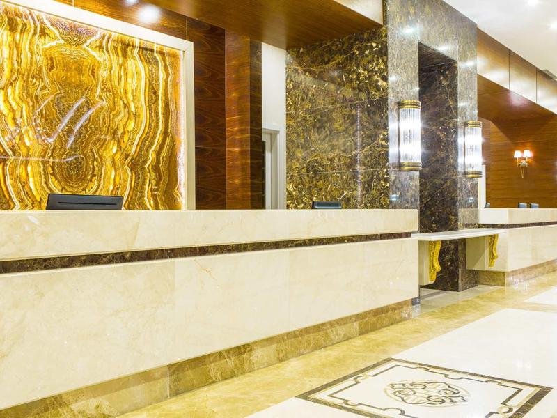 Réception d'hôtel moderne avec comptoir en marbre et murs décoratifs lumineux.