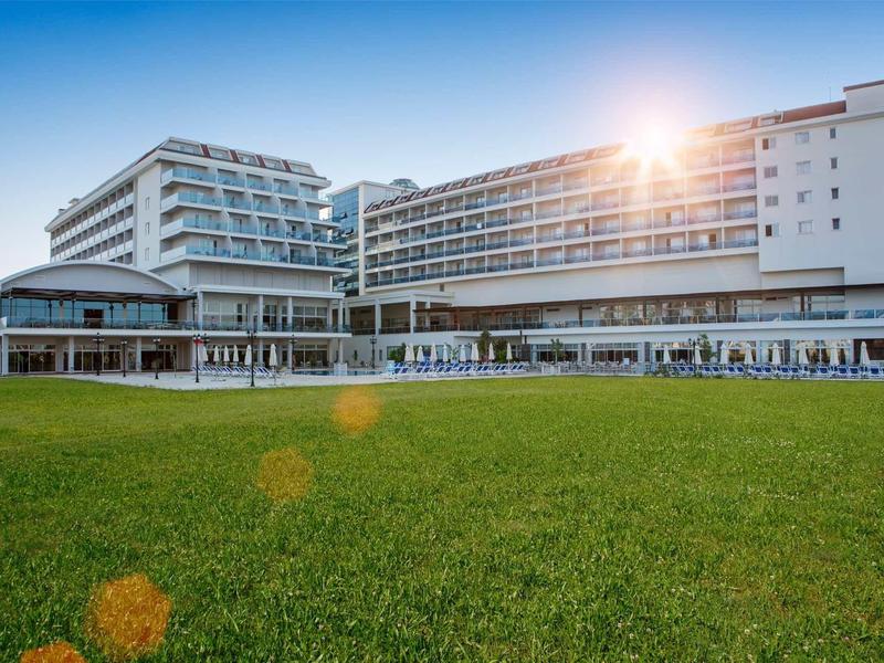 Hôtel moderne avec grand espace vert sous un soleil radieux.