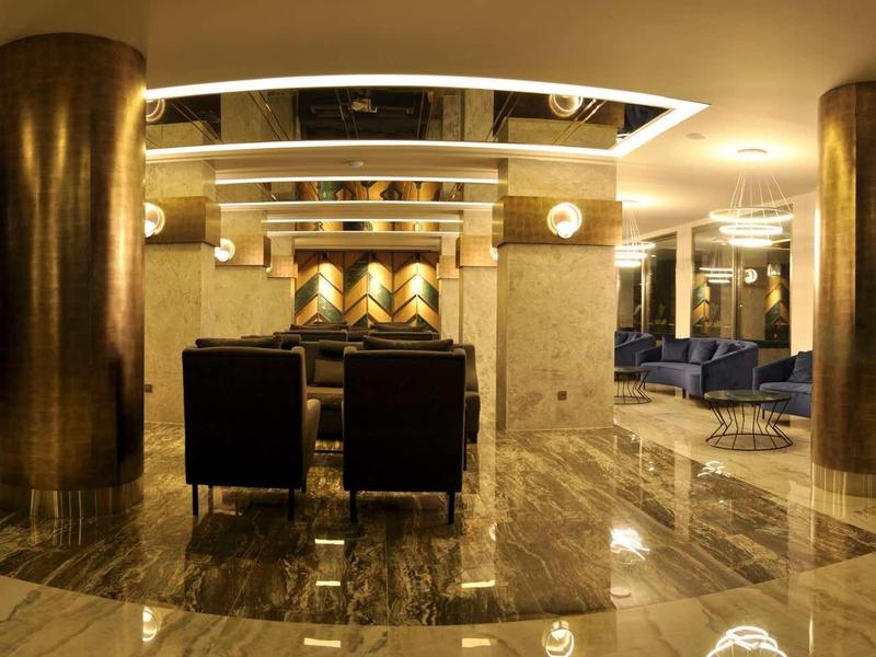 Modern hotel lobby with shiny marble floor and stylish seating areas.