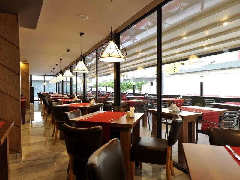 Modern outdoor restaurant area with stylish tables and chairs next to a covered terrace.