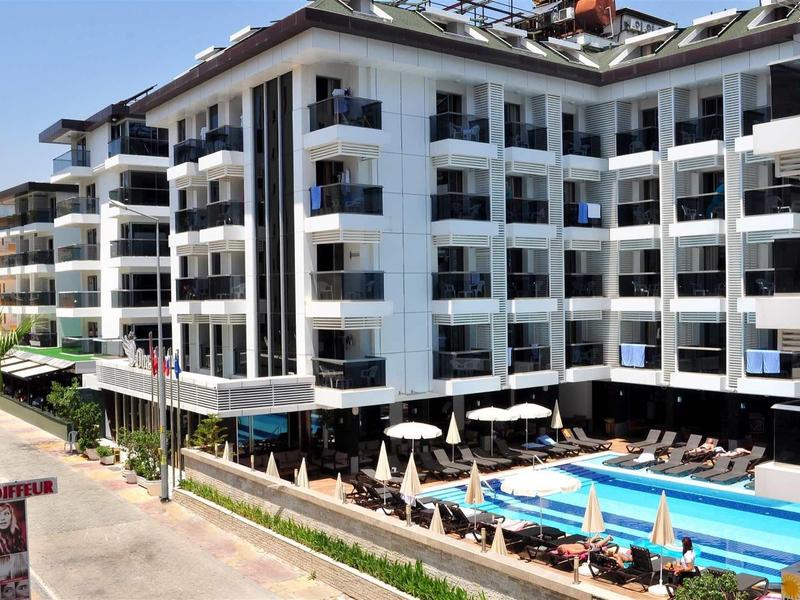 Modern hotel with multiple floors, balconies, and an outdoor pool beside the terrace.