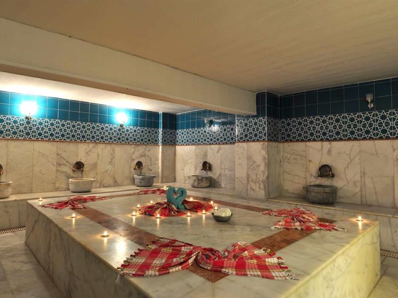 Traditional Turkish hammam with marble slab in the center and wall fountains.