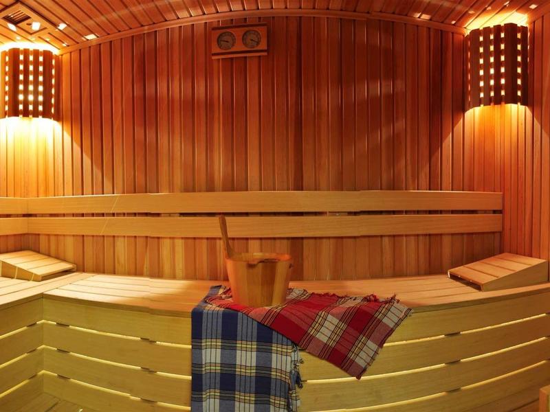 Cozy sauna with wooden benches, bucket, and towels under warm lighting.