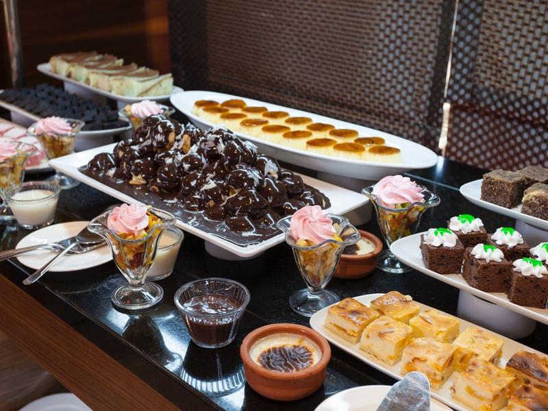 Bufé con varios postres, incluyendo pastel de chocolate, cupcakes y crème brûlée.