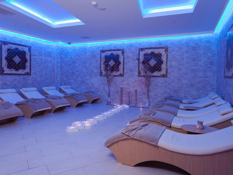 Sala de relajación con tumbonas curvas y luz ambiental azul en un área de spa.