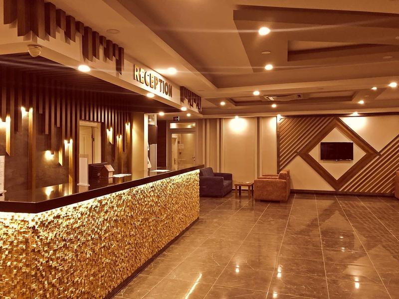 Modern hotel lobby with illuminated reception desk and cozy seating areas.