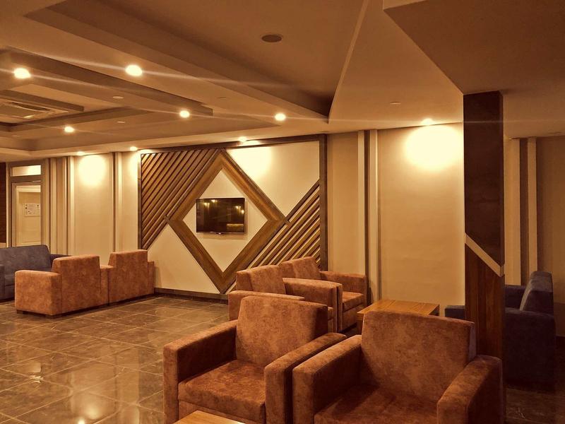 Cozy lobby with brown armchairs, lighting, and decorative wall panels in a hotel.