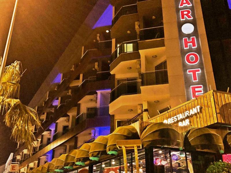 Exterior view of a hotel at night with illuminated sign and covered entrance.