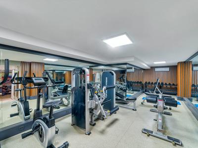 Modern fitness room with various exercise machines and mirrored wall in a hotel.