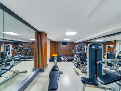 Modern gym with various workout machines and a mirror wall in a hotel.