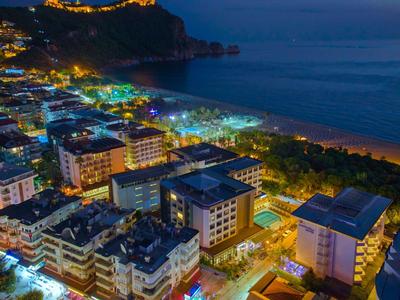 Pobřežní město v noci s osvětlenými budovami a pláží u klidného moře.