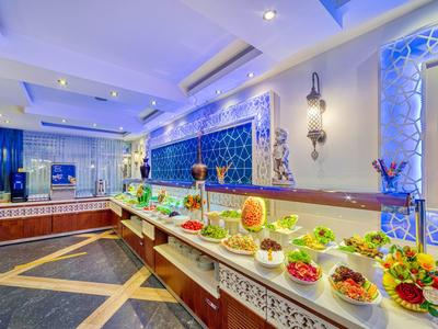 Bufet s různými čerstvými jídly a dekorativním modrým pozadím v hotelové restauraci.