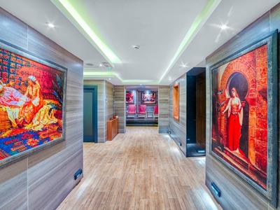 Chodba s dřevěnou podlahou a barevnými obrazy na stěnách v moderním hotelu.