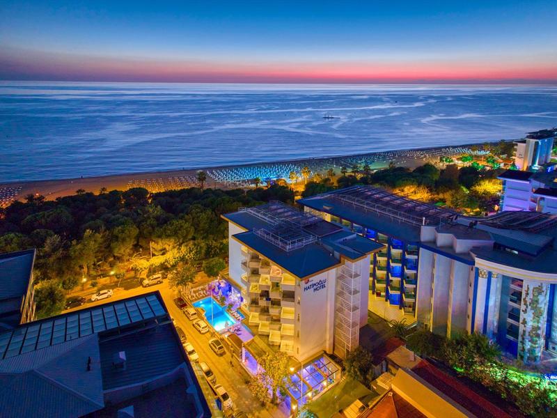 Pohled na osvětlené hotely a pláž při západu slunce u moře.