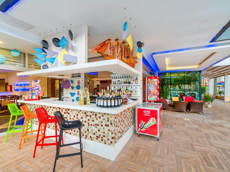 Moderní hotelový bar s barevnými židlemi, stylovým barem a posezením v světlé místnosti.