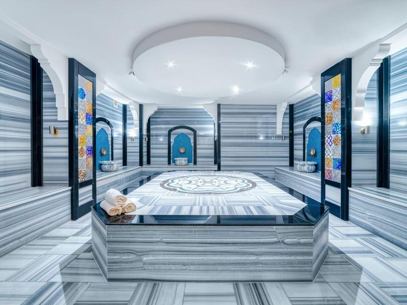 Moderní luxusní místnost s mramorovým vzhledem a centrální postelí s vzorovaným povrchem.