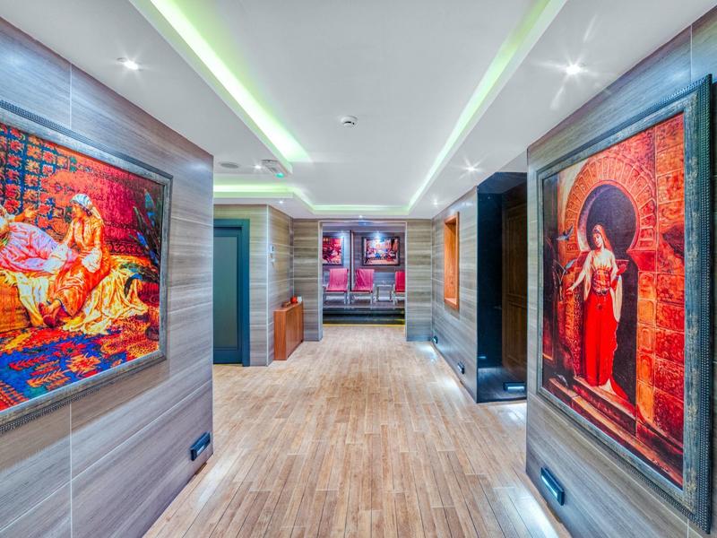 Chodba s dřevěnou podlahou a barevnými obrazy na stěnách v moderním hotelu.