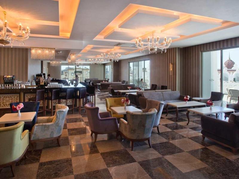 Elegant hotel dining area with modern armchairs, wooden floor, and chandeliers.