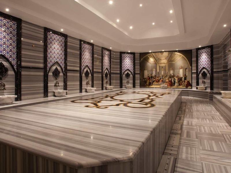 Luxurious hammam with marble basins and intricate mosaics on the walls.