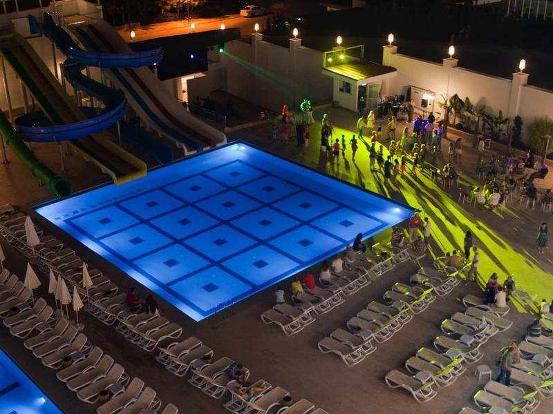 Illuminated swimming pools and guest areas at night in a hotel resort.