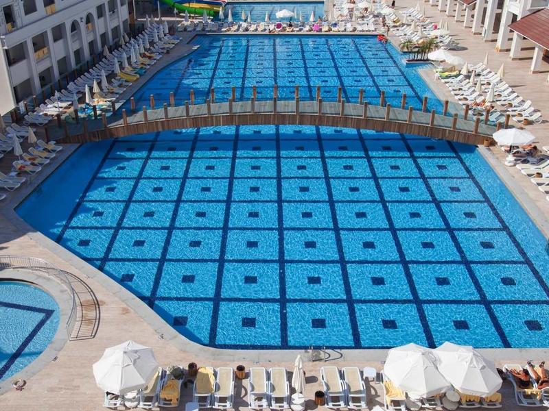 Large outdoor pool with geometric pattern and sun loungers at a hotel.