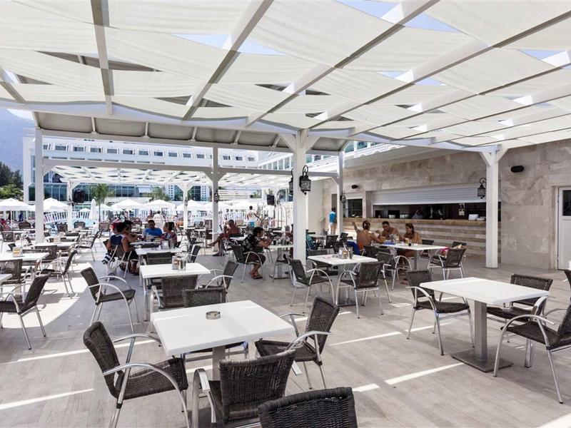 Large covered terrace with many tables and chairs, some guests sitting relaxed.