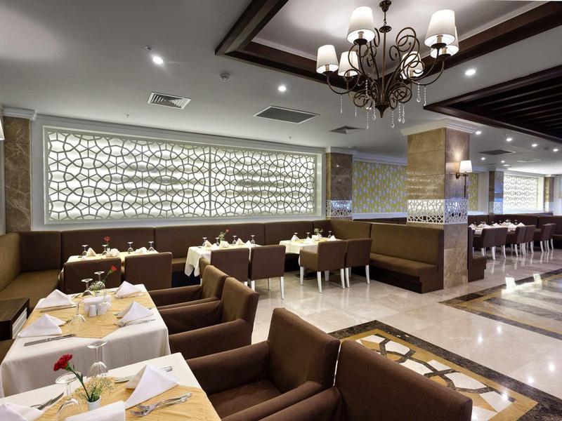 Modern dining area with brown booths, white tablecloths, and chandeliers.