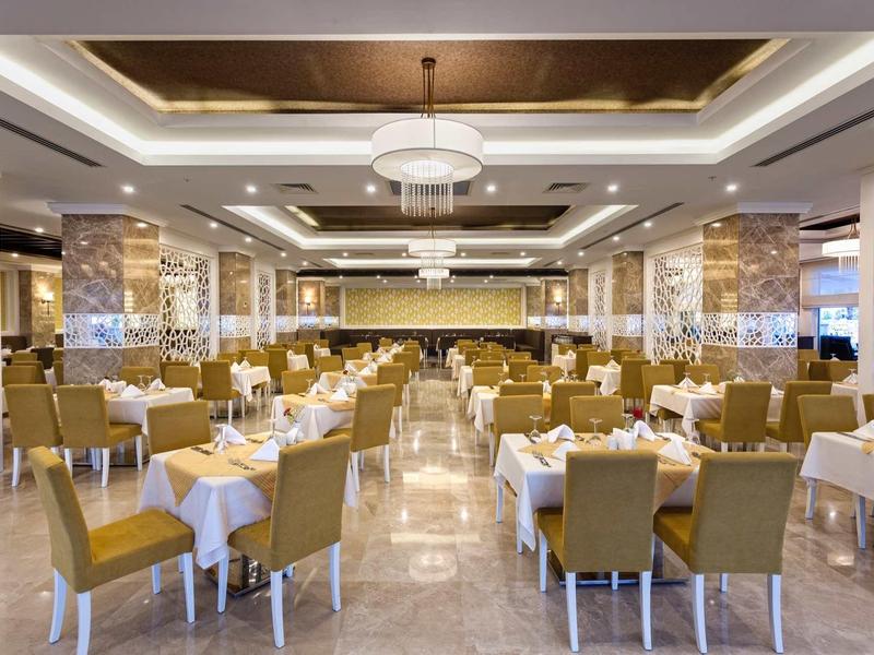Elegant restaurant with set tables and comfortable yellow chairs in a luxurious hotel.