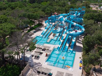 Großer Wasserpark mit blauen Wasserrutschen, Pools und umliegendem Waldgebiet.