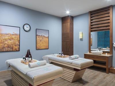 Moderner Wellnessraum mit zwei Massageliegen, Handtüchern und entspannter Beleuchtung.