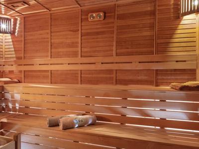 Helle, hölzerne Sauna mit zwei Lampen und mehreren Sitzbänken für Entspannung.