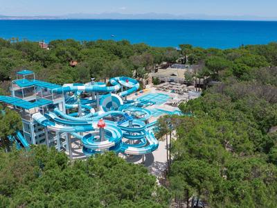 Blick auf ein großes Wasserrutschen-Areal in einer bewaldeten Hotelanlage am Meer.
