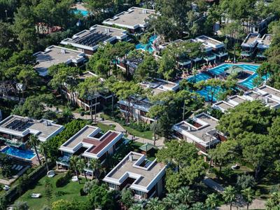 Luftaufnahme eines Hotelkomplexes mit mehreren Pools und umgeben von dichtem Grün.