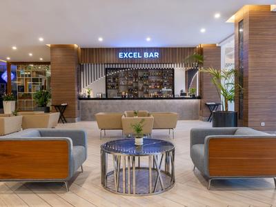 Moderne Hotelbar mit Sitzbereich und Holz- sowie Metallakzenten in neutralen Farben.