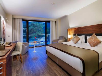 Modernes Hotelzimmer mit großem Bett, Sitzbereich und Blick auf den Balkon.