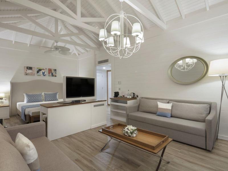 Modern living room with sofa, TV, and wood ceiling with exposed beams.
