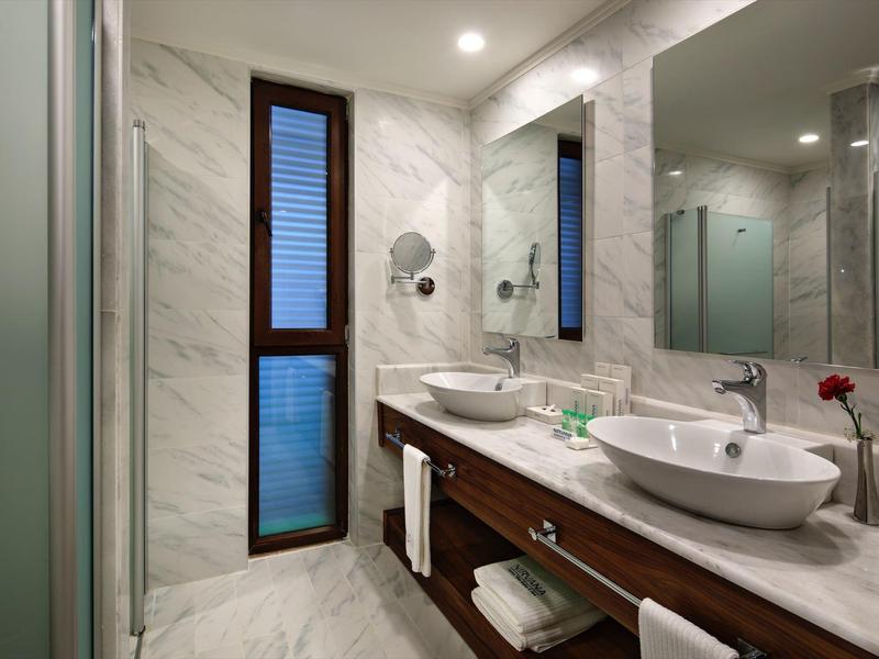 Modern bathroom with double sinks and large mirror in a hotel room.