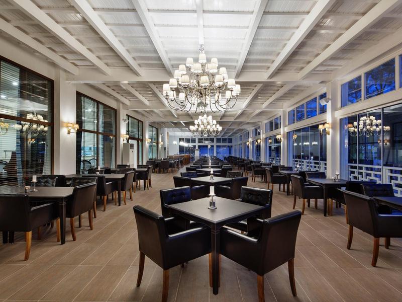 Elegant hotel restaurant with black furniture, wooden floor, and large chandeliers.