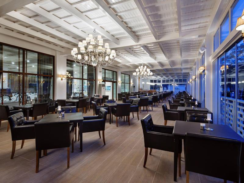 Elegant restaurant with modern black chairs and large windows at dusk.