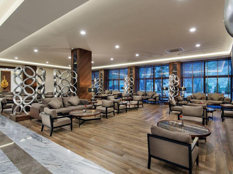 Spacious hotel lobby with modern armchairs and large windows in daylight.