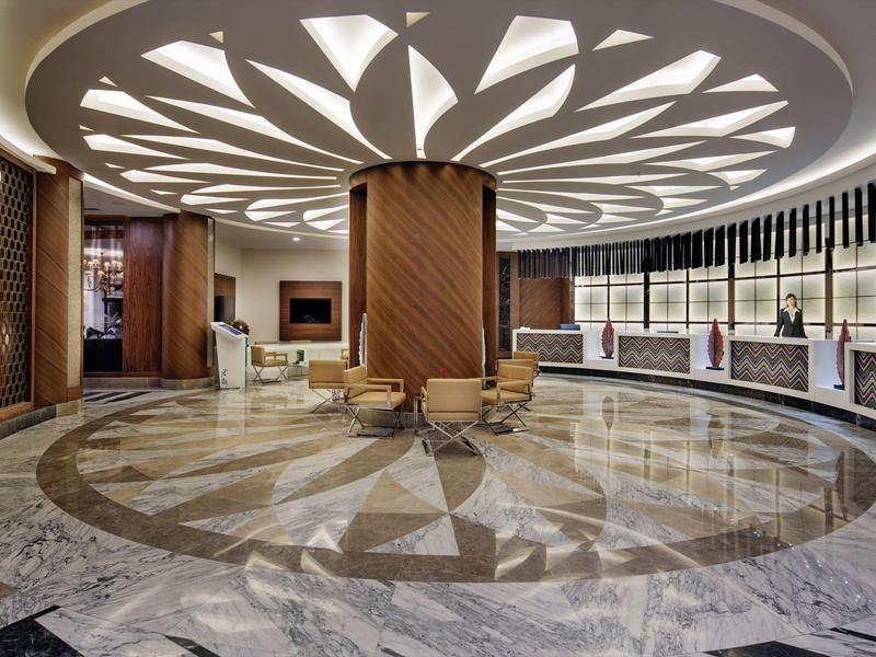 Elegant circular lobby with patterned marble floor and striking ceiling lighting.