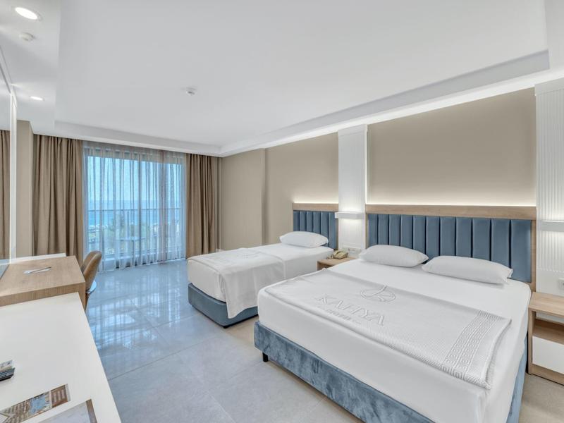 Modern hotel room with two beds, large window, and elegant, bright interior.