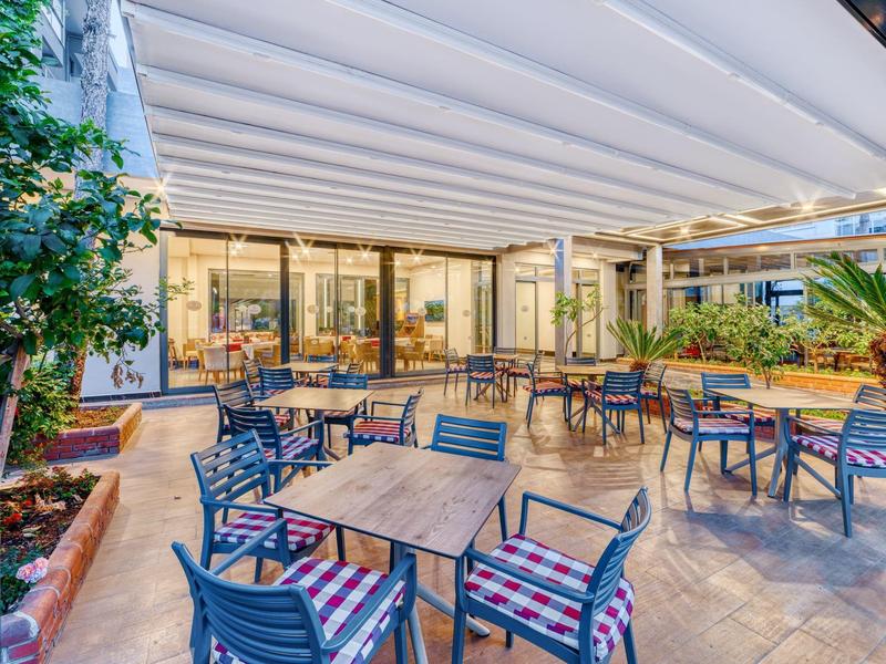 Hotel terrace with tables, chairs, and a white canopy for outdoor guest seating.