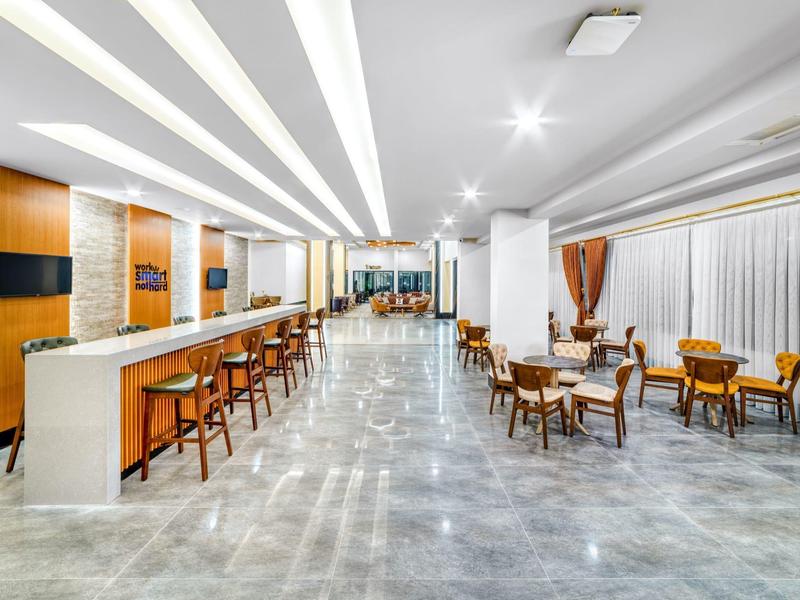 Spacious hotel lobby with bar and seating areas, modern and bright design.