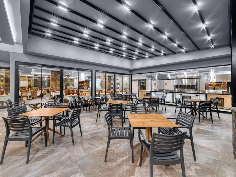 Modern dining area with tables and chairs, large glass front, and bright lighting.