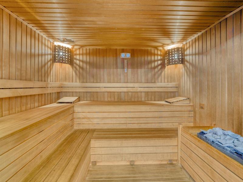 Cozy sauna with solid wooden benches and warm wall lighting.