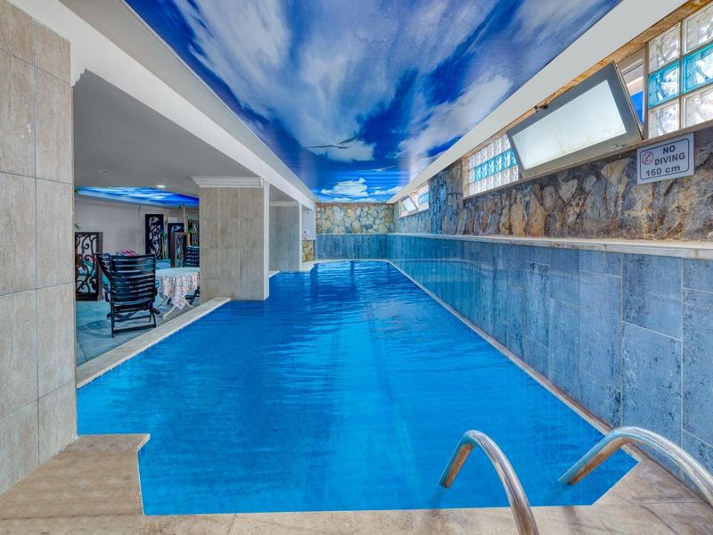 Indoor pool with a vivid painted sky on the ceiling and stylish design.