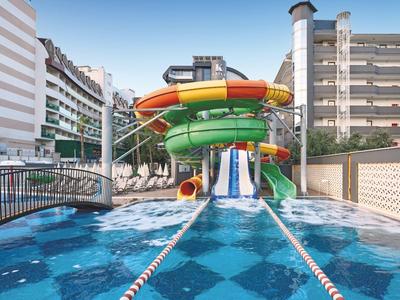 Buntes Wasserrutschenbecken zwischen Hotelgebäuden mit Sonnenschirmen im Freien
